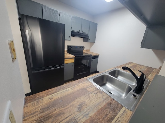 kitchen with black appliances, under cabinet range hood, a sink, light wood finished floors, and gray cabinets