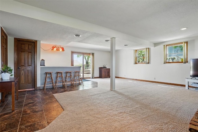 carpeted living room featuring a textured ceiling, baseboards, and bar