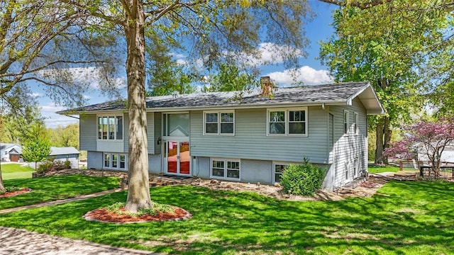 raised ranch with a chimney and a front lawn