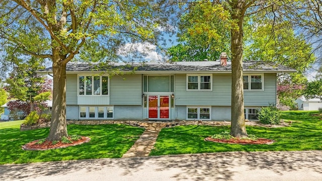 bi-level home featuring a chimney and a front lawn