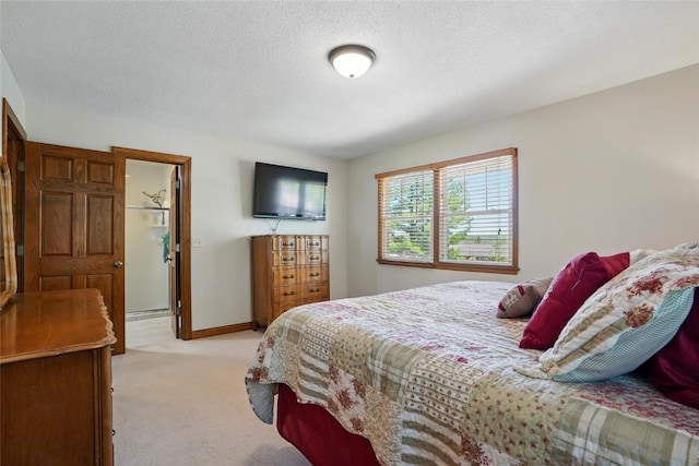 bedroom featuring light colored carpet, baseboards, and a textured ceiling