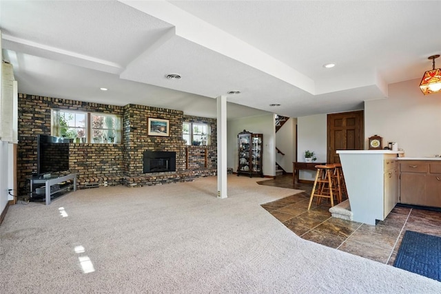 living room with healthy amount of natural light, stairway, a brick fireplace, dark carpet, and brick wall