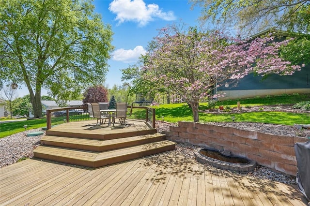 wooden terrace featuring outdoor dining area and a yard