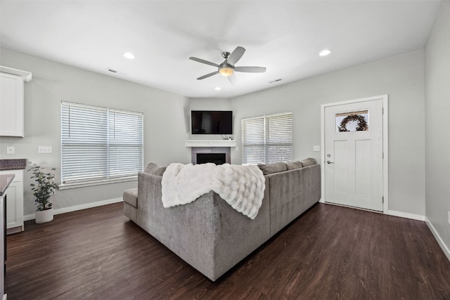 living room featuring dark wood-type flooring, a ceiling fan, a fireplace, baseboards, and recessed lighting