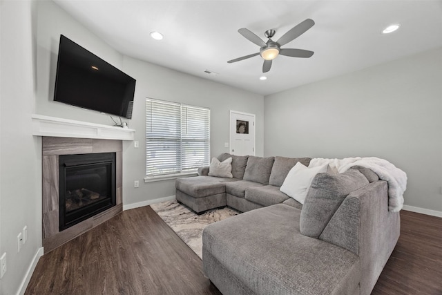 living room with a glass covered fireplace, wood finished floors, baseboards, recessed lighting, and ceiling fan