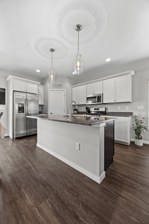 kitchen with stainless steel appliances, a sink, dark wood-type flooring, recessed lighting, and an island with sink