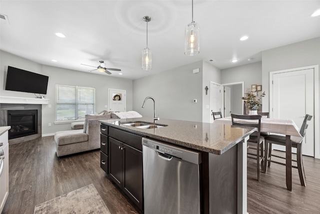 kitchen featuring stainless steel dishwasher, a sink, dark wood-type flooring, ceiling fan, and light stone counters