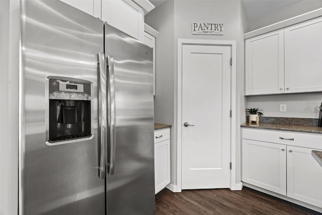 kitchen with stainless steel fridge, dark wood-style floors, white cabinets, and dark stone counters
