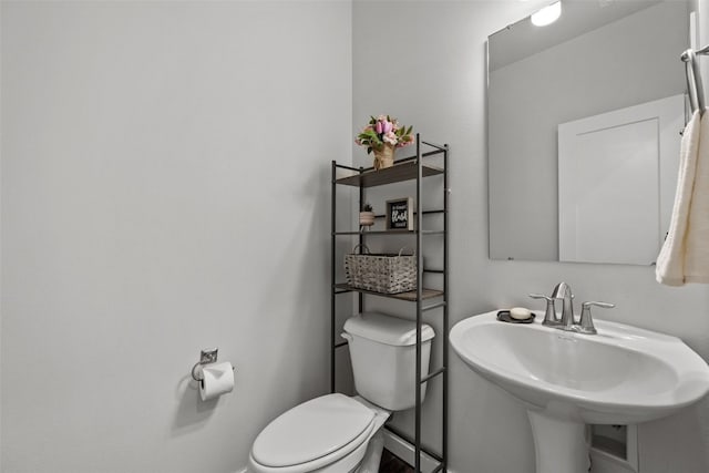 bathroom with toilet, a sink, and baseboards