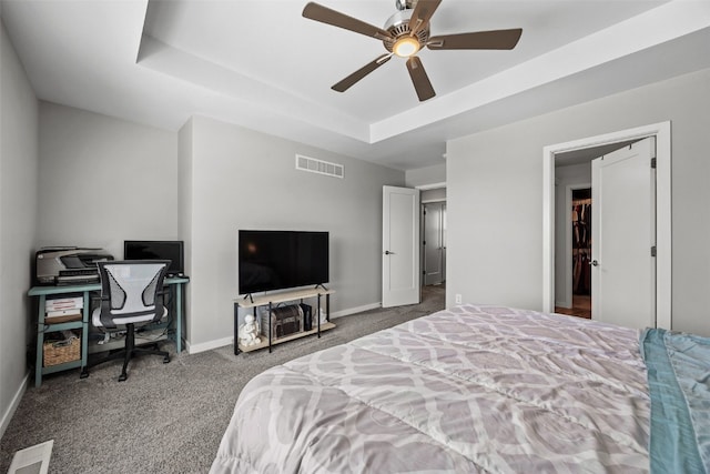carpeted bedroom with a raised ceiling, baseboards, an office area, and ceiling fan