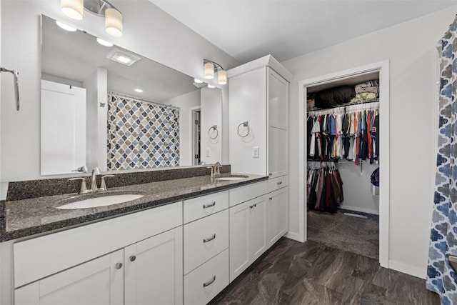 bathroom featuring double vanity, baseboards, a walk in closet, and curtained shower