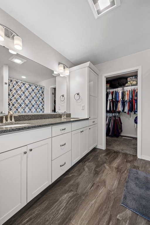 full bath featuring double vanity, a walk in closet, and curtained shower