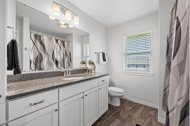 bathroom with plenty of natural light, toilet, baseboards, and vanity