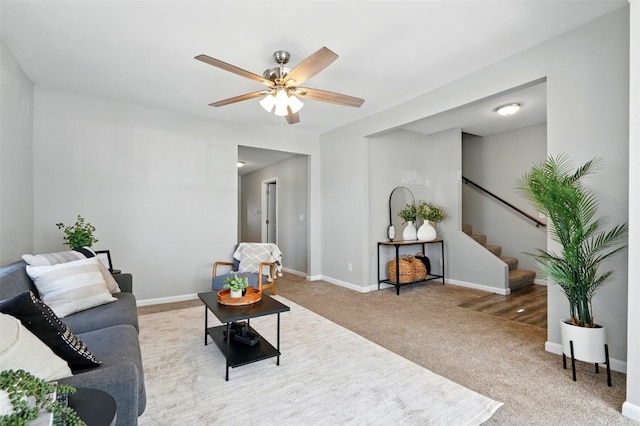 carpeted living room with a ceiling fan, stairway, and baseboards
