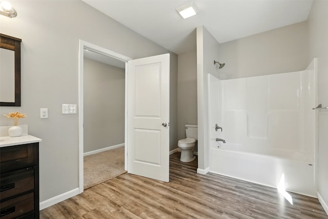 bathroom with wood finished floors, toilet, vanity, shower / bathtub combination, and baseboards