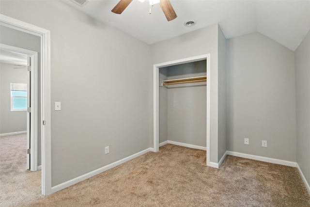 unfurnished bedroom with light colored carpet, a closet, baseboards, vaulted ceiling, and ceiling fan