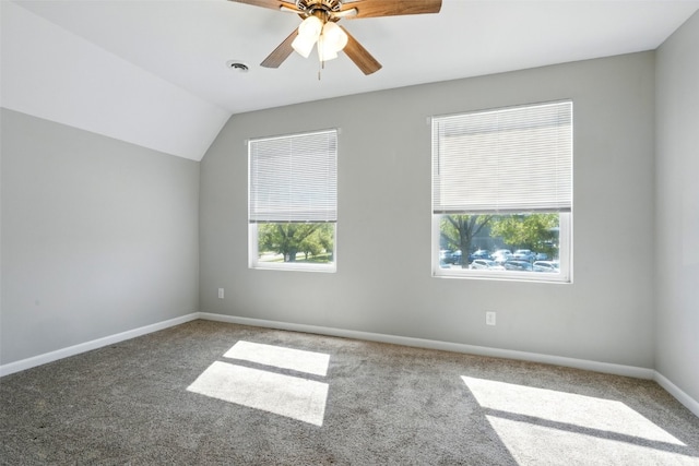 carpeted spare room with a ceiling fan, baseboards, and vaulted ceiling