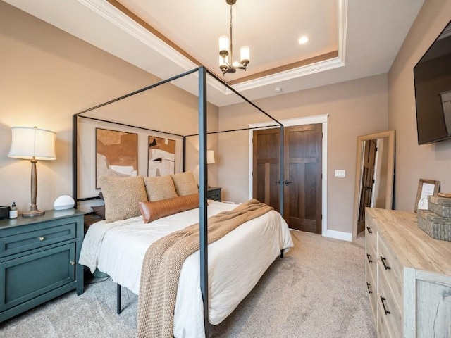 bedroom with light colored carpet, a chandelier, a closet, baseboards, and a tray ceiling