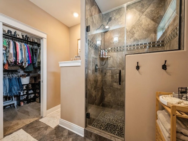 bathroom with a stall shower, a spacious closet, and baseboards