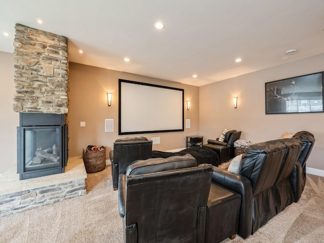 home theater room featuring light colored carpet, recessed lighting, a stone fireplace, and baseboards