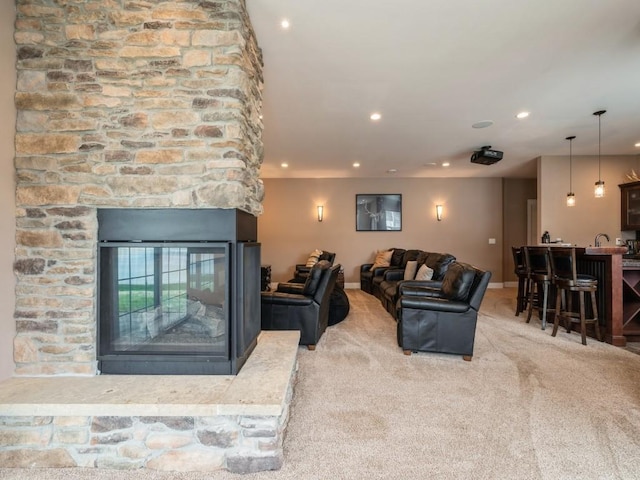 carpeted living area featuring recessed lighting, a stone fireplace, and baseboards
