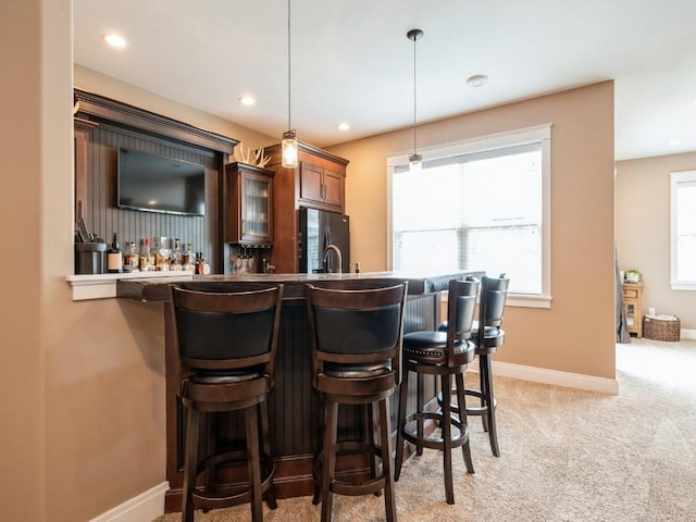 indoor bar with freestanding refrigerator, pendant lighting, baseboards, light colored carpet, and recessed lighting