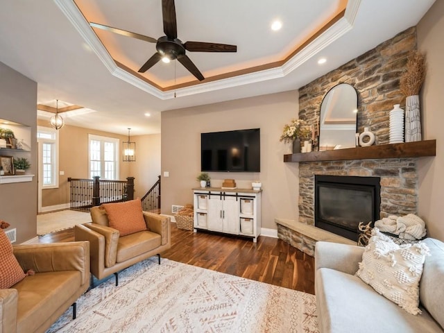 living room featuring a tray ceiling, crown molding, ceiling fan, wood finished floors, and baseboards