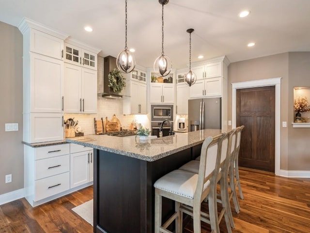 kitchen featuring appliances with stainless steel finishes, wall chimney range hood, baseboards, backsplash, and dark wood-style flooring