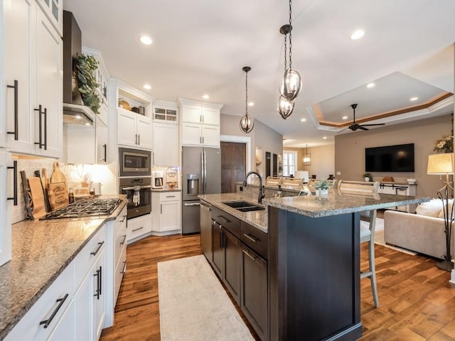 kitchen with a sink, appliances with stainless steel finishes, ceiling fan, open floor plan, and a breakfast bar area