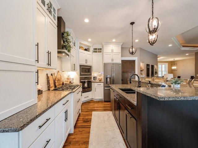 kitchen featuring stainless steel appliances, a sink, wall chimney exhaust hood, decorative backsplash, and recessed lighting