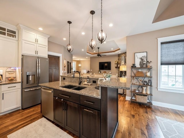 kitchen with stainless steel appliances, a sink, open floor plan, white cabinetry, and dark wood-type flooring