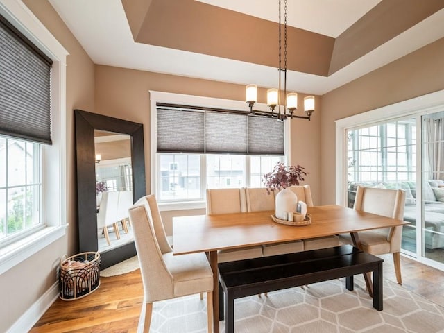 dining space featuring a chandelier, light wood-type flooring, and baseboards