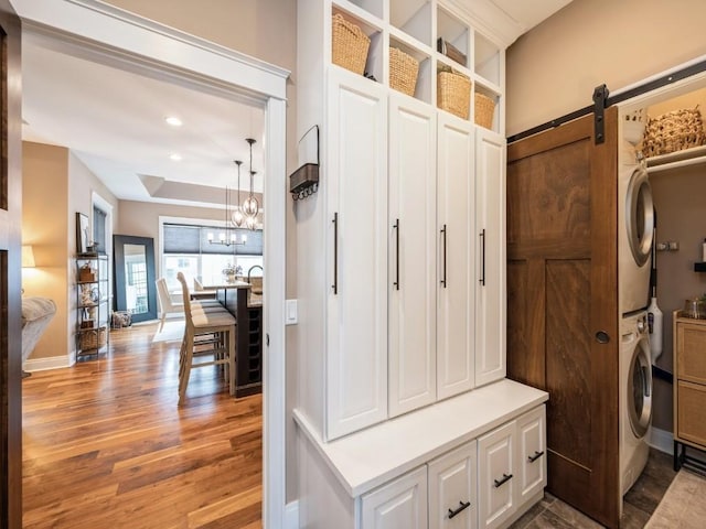 mudroom with stacked washing machine and dryer, light wood-style flooring, a chandelier, baseboards, and recessed lighting