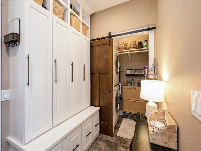 mudroom with stacked washing machine and dryer and a barn door