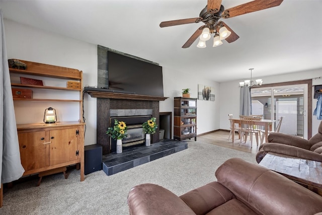 carpeted living room featuring ceiling fan, a tile fireplace, and a chandelier