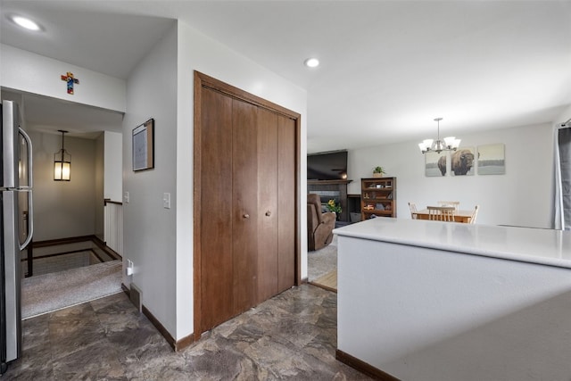 kitchen featuring freestanding refrigerator, a chandelier, a tile fireplace, baseboards, and pendant lighting