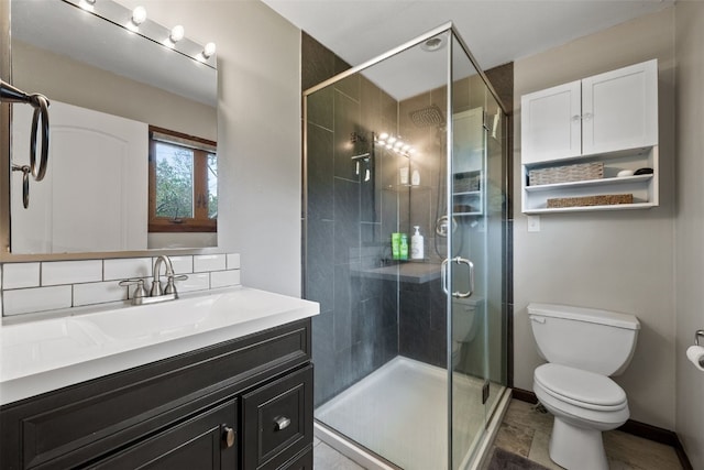 full bath featuring toilet, a stall shower, vanity, decorative backsplash, and baseboards