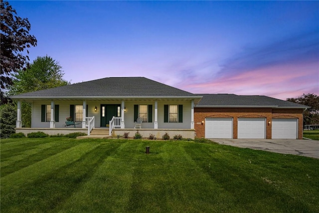 view of front of house featuring driveway, an attached garage, covered porch, and a front yard
