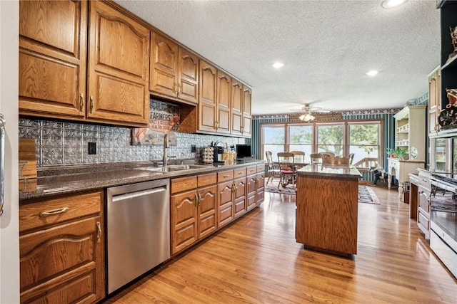 kitchen with dishwasher, a sink, a textured ceiling, ceiling fan, and dark countertops