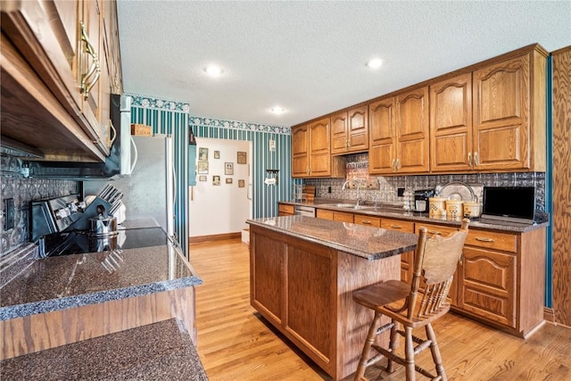 4030 Bruce Rd, Marion, IA 52302 - kitchen with range, a center island, light wood-style flooring, a sink, and a textured ceiling