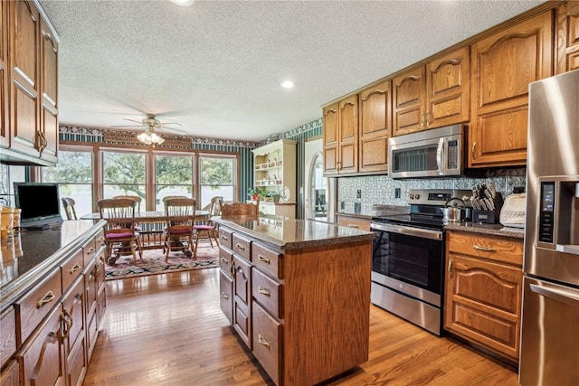 4030 Bruce Rd, Marion, IA 52302 - kitchen with stainless steel appliances, a textured ceiling, ceiling fan, a kitchen island, and brown cabinets