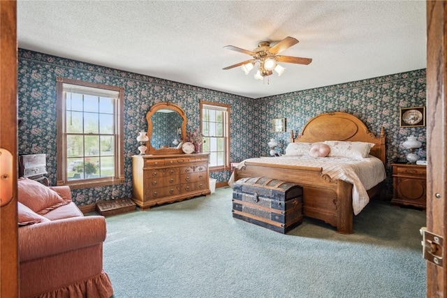 carpeted bedroom with wallpapered walls, multiple windows, a textured ceiling, and ceiling fan