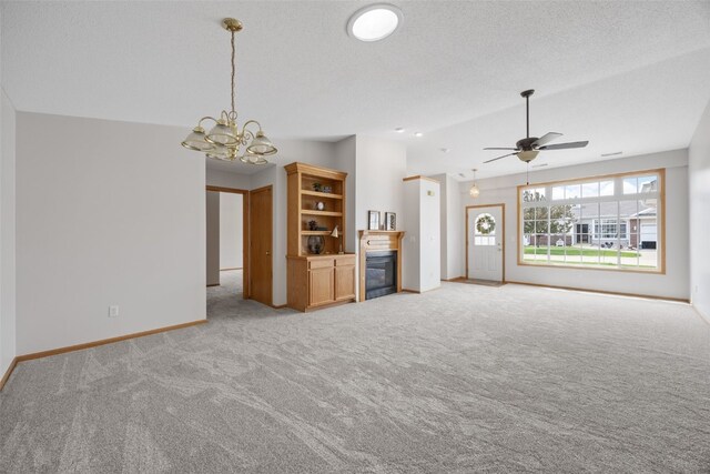 unfurnished living room featuring light colored carpet, a chandelier, lofted ceiling, baseboards, and ceiling fan