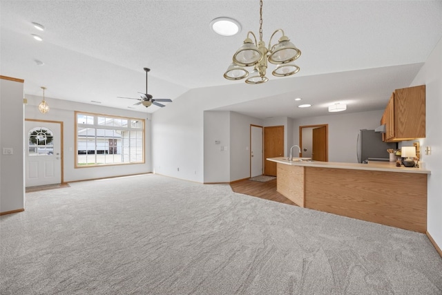 unfurnished living room featuring light carpet, vaulted ceiling, a sink, baseboards, and a ceiling fan