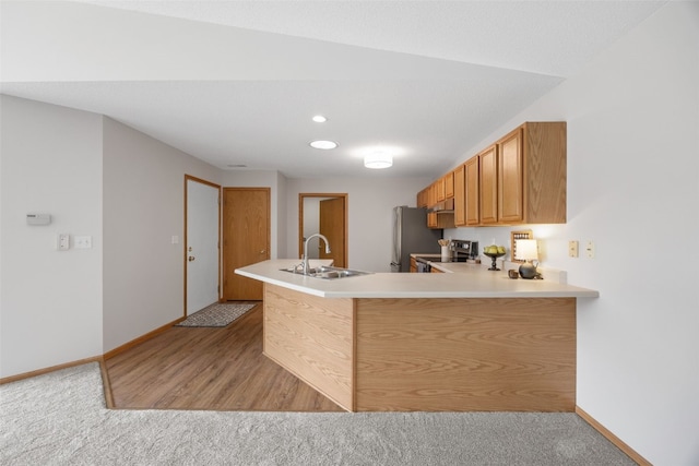 kitchen with stainless steel appliances, a sink, baseboards, and light countertops