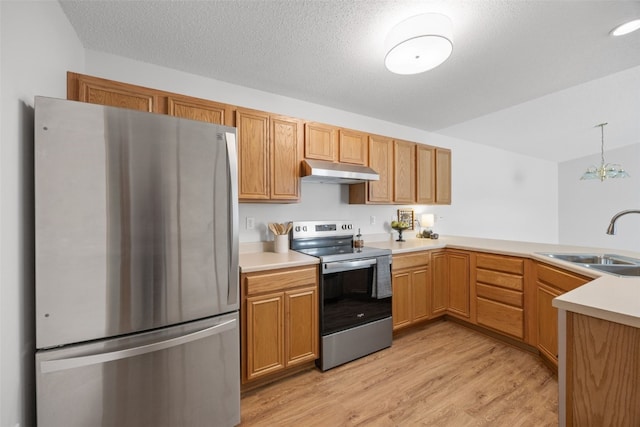 kitchen featuring stainless steel appliances, a sink, under cabinet range hood, light countertops, and light wood finished floors