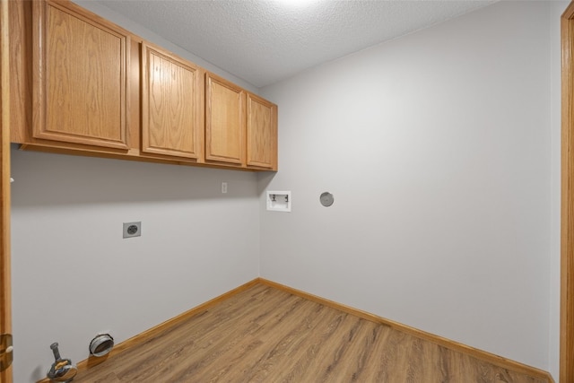 washroom featuring hookup for an electric dryer, cabinet space, light wood-style floors, hookup for a washing machine, and baseboards