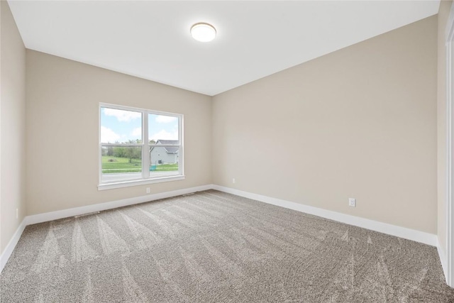 carpeted empty room featuring baseboards