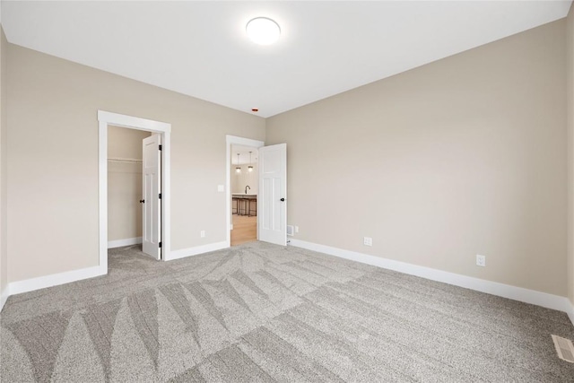 unfurnished bedroom featuring carpet floors, baseboards, a spacious closet, and a closet
