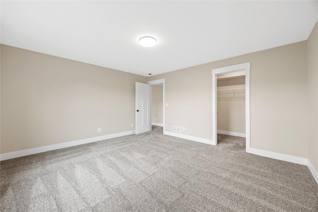 unfurnished bedroom featuring baseboards, light carpet, a closet, and a spacious closet